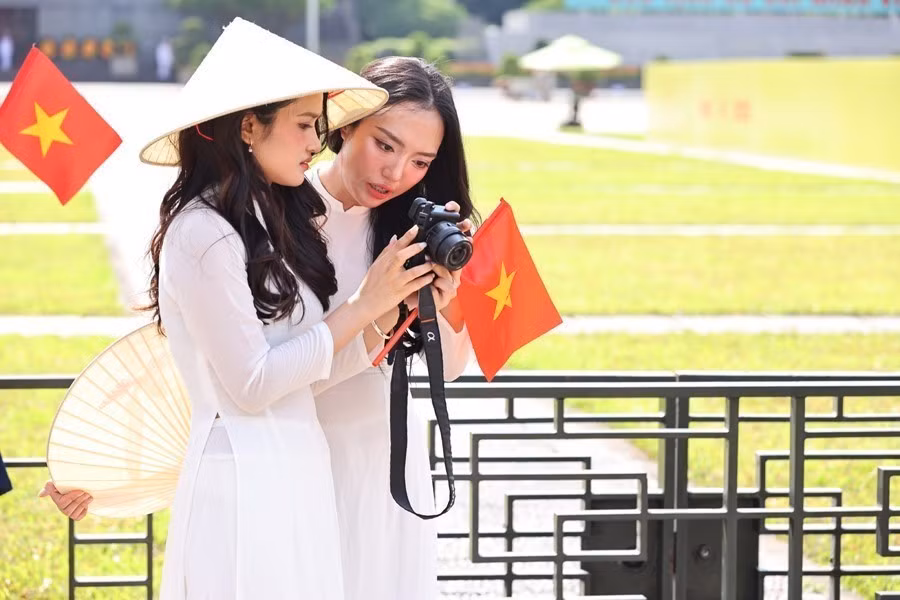 De jeunes femmes revêtent l'ao dai, la tenue traditionnelle vietnamienne, pour célébrer le 80e anniversaire de la Révolution d'août et de la Fête nationale. Photo : VNA