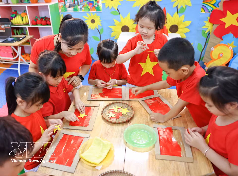 Avec enthousiasme, minutie et application, les élèves de maternelle réalisent le drapeau national, symbole sacré de la nation vietnamienne. Photo : VNA