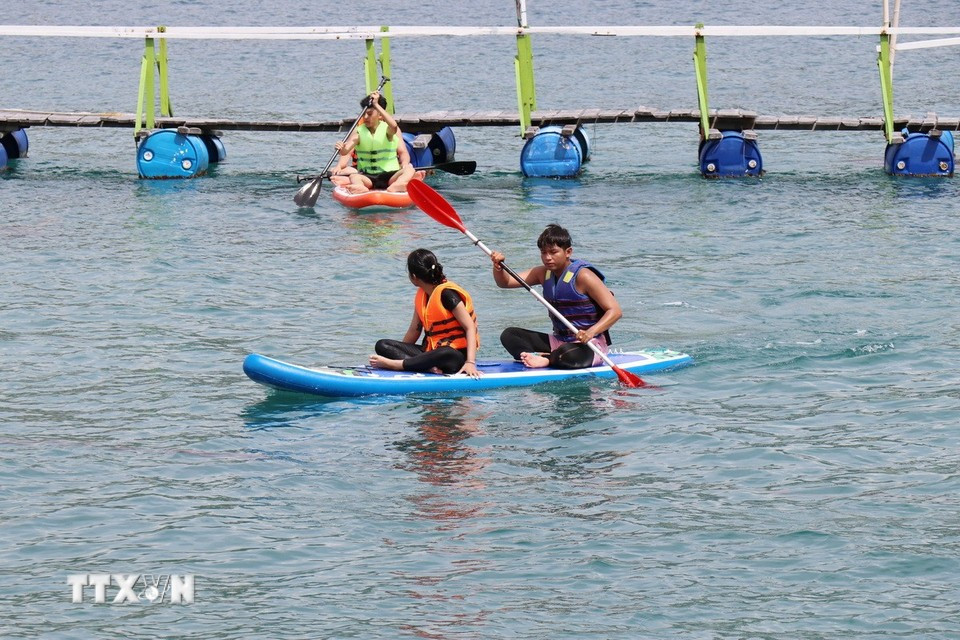 Les visiteurs peuvent pratiquer des activités comme le kayak, sur la baie de Vinh Hy. Photo : VNA