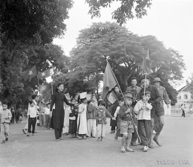Des enfants de Hanoï, accompagnés de leurs proches, agitent des drapeaux, célébrant l'arrivée des soldats libérateurs. Photo : Archives