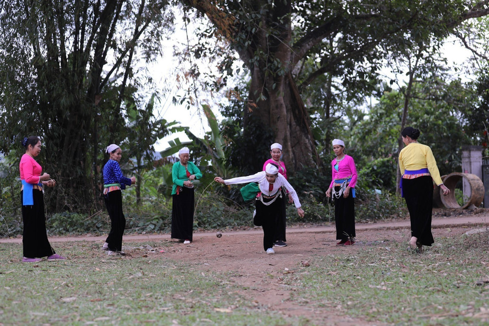 La technique consiste à enrouler une cordelette autour de la toupie, puis à la projeter d’un geste vif afin de déclencher sa rotation sur le sol. Photo : VNA