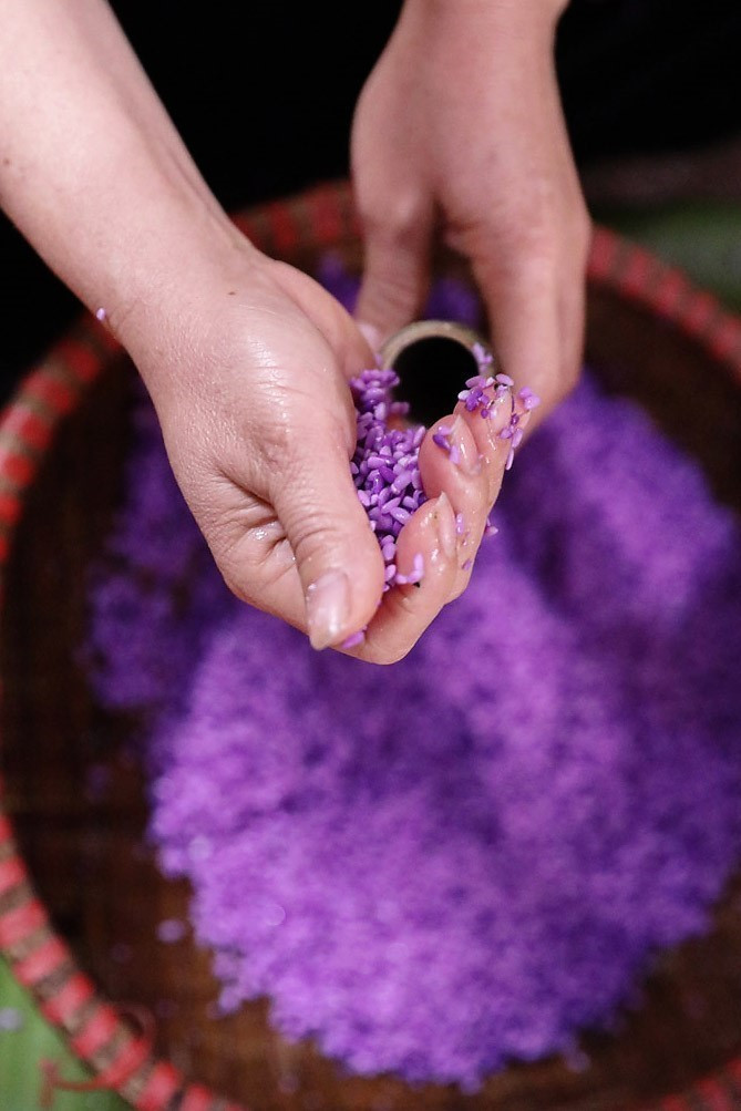 Incontournable de la table de fête, le "com lam" (riz gluant cuit dans des tubes de bambou) se distingue par sa couleur violette naturelle, obtenue grâce à des plantes tinctoriales locales. Photo : VNA