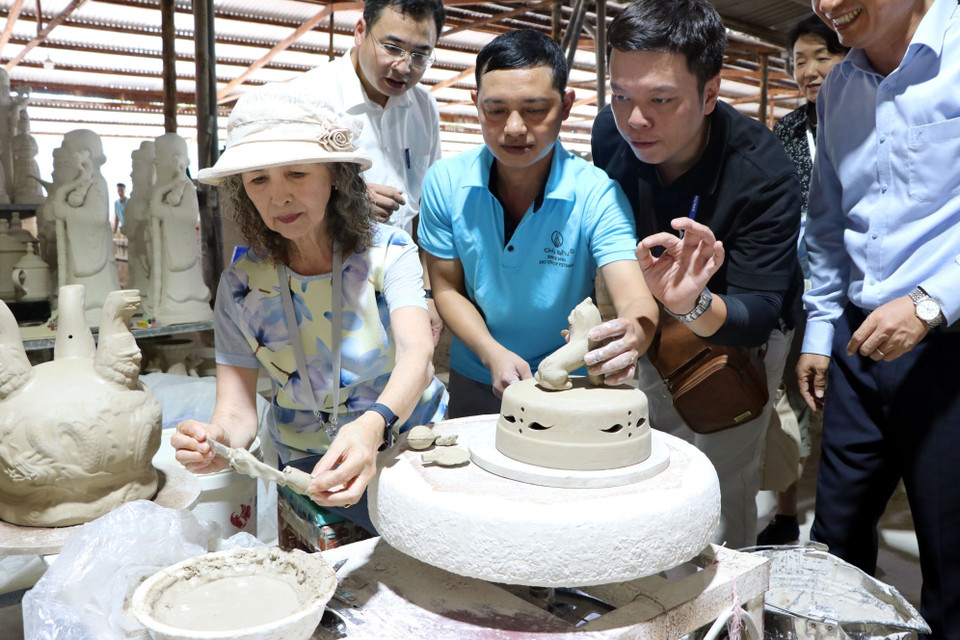 Les invités internationaux découvrent le processus de production de la céramique Chu Dâu. Chaque produit subit un processus rigoureux en cinq étapes : préparation de l'argile, façonnage, décoration des motifs, émaillage et cuisson. Photo : Manh Tu – VNA