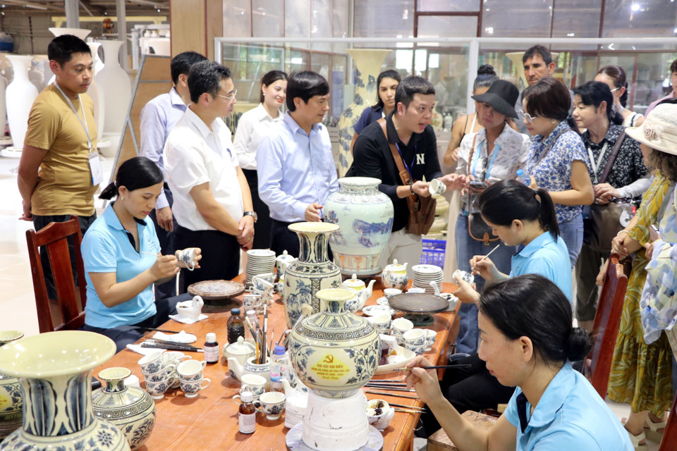 Un représentant de la société par actions de poterie de Chu Dâu présente des motifs en céramique aux invités internationaux. Photo : Manh Tu - VNA