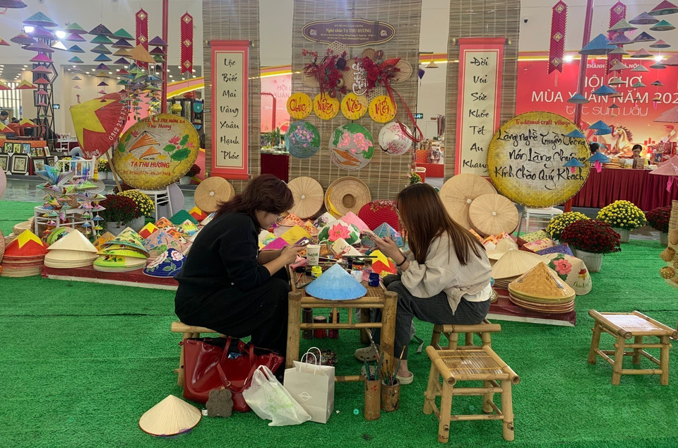 Le stand de chapeaux coniques de Chuong attire de nombreux jeunes venus dessiner et prendre des photos pour le Têt. Photo : VNA