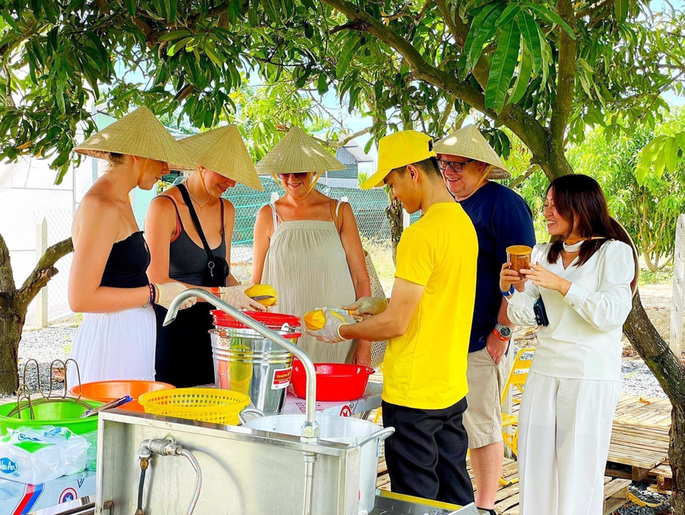 Les visiteurs étrangers apprécient de pouvoir s'initier à la fabrication de produits dérivés de la mangue, directement à l'ombre des arbres fruitiers. Photo : VNA