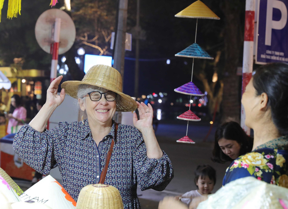 Une touriste admire l'artisanat traditionnel vietnamien lors du Festival des cadeaux touristiques de Hanoï 2025, témoignant de l'attrait des produits locaux.Photo : VNA