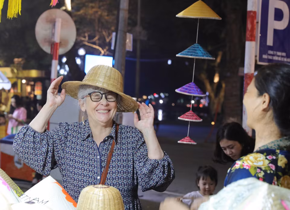 Une touriste admire l'artisanat traditionnel vietnamien lors du Festival des cadeaux touristiques de Hanoï 2025, témoignant de l'attrait des produits locaux.Photo : VNA