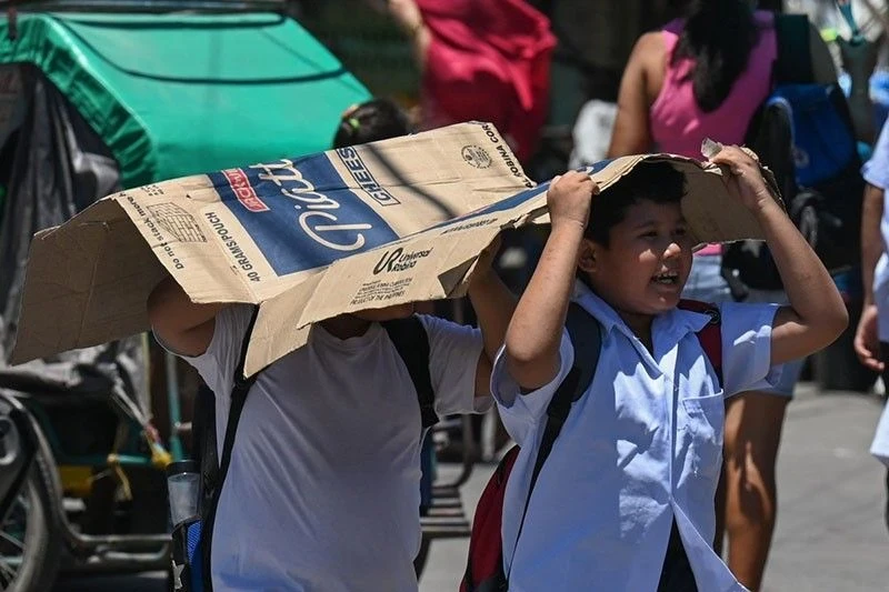 Des étudiants utilisent un carton pour se protéger du soleil lors d'une chaude journée à Manille le 2 avril 2024. (Photo : philstar.com)
