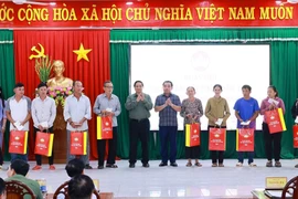 Le Premier ministre Pham Minh Chinh remet des cadeaux à des familles bénéficiaires de politiques sociales. Photo: VNA