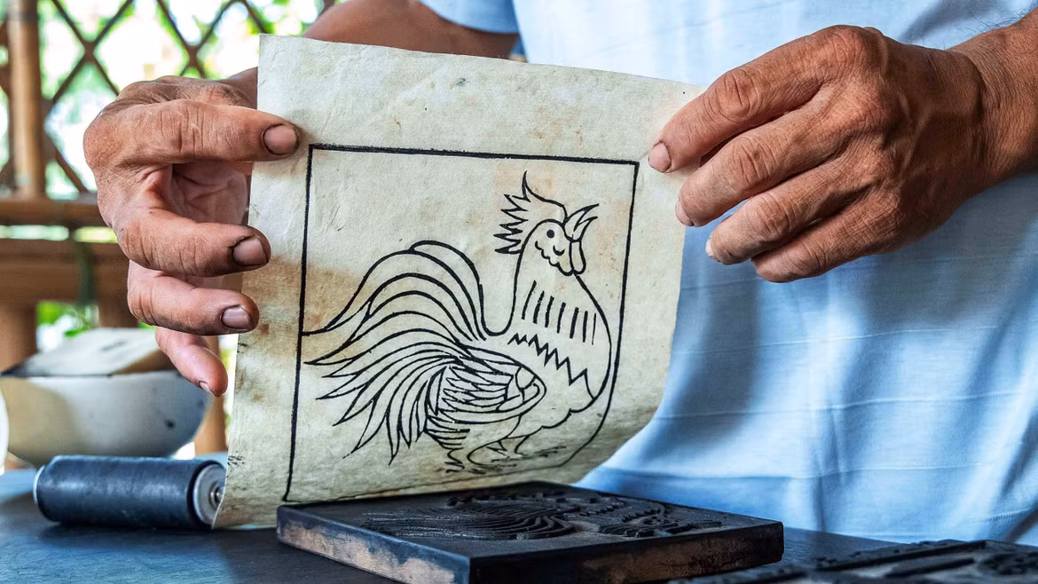 Contrairement aux estampes polychromes, la peinture de Sinh utilise la matrice uniquement pour imprimer les contours, la coloration étant ensuite réalisée à la main, ce qui rend chaque œuvre unique. Photo : VNA
