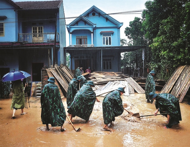Des officiers et des soldats du commandement militaire du district de Son Dông, province de Bac Giang, aident les habitants à nettoyer l’environnement après le retrait des eaux de crue. Photo: VNA
