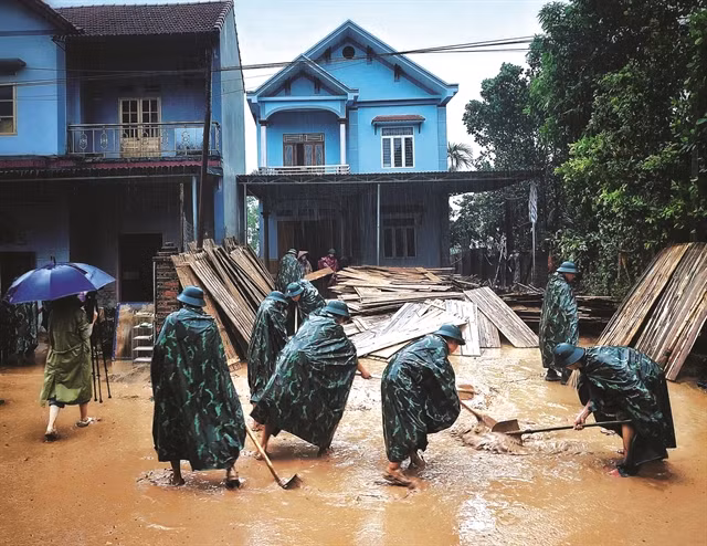 Des officiers et des soldats du commandement militaire du district de Son Dông, province de Bac Giang, aident les habitants à nettoyer l’environnement après le retrait des eaux de crue. Photo: VNA