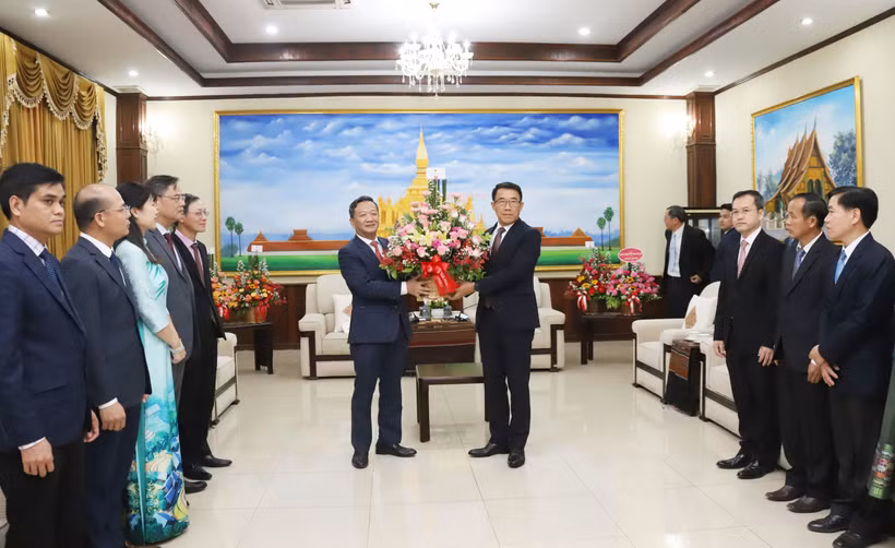L'ambassadeur Nguyen Minh Tam remet des fleurs de félicitations du secrétaire général To Lam à la partie lao. Photo : VNA