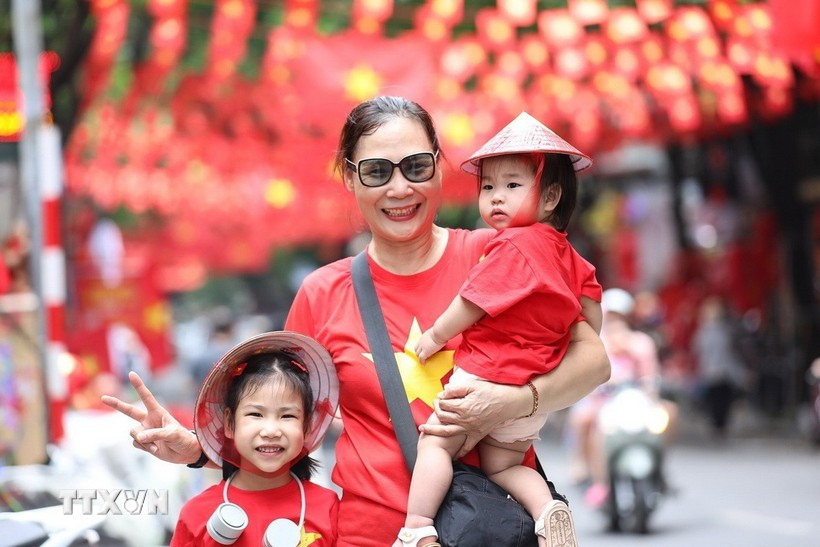 De nombreuses personnes ont immortalisé l'instant avec l'image du drapeau national sur la rue Hang Ma, dans le quartier Hoan Kiem, à Hanoï. Photo : VNA