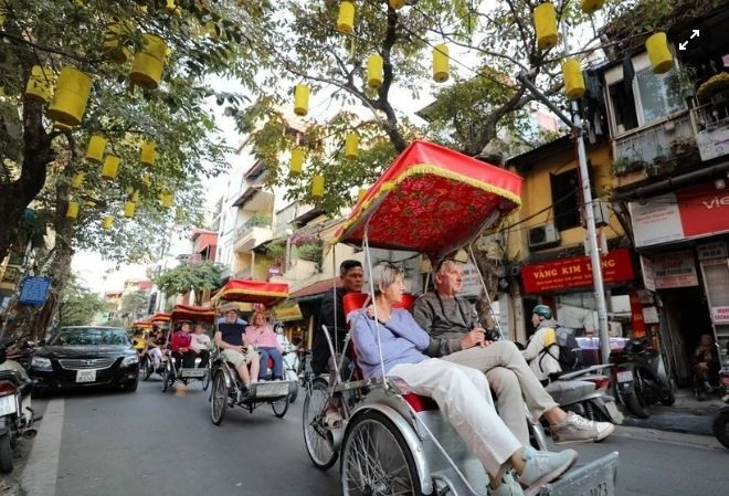 Les touristes étrangers visitent les rues en cyclo-pousse, admirant la beauté antique d'Hanoï. Photo : VNA