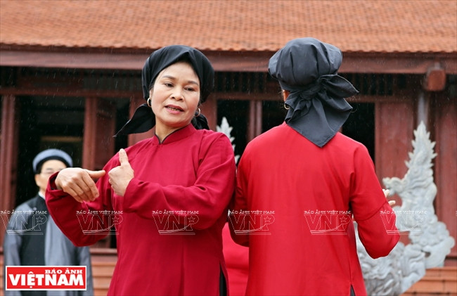 Le costume de la chanteuse de Hat xoan se compose d’une tunique traditionnelle rouge et d’un foulard traditionnel dit en « bec de corbeau » (mỏ quạ).