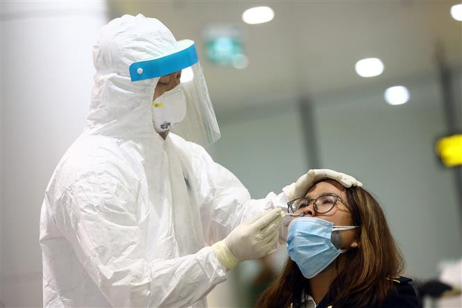 Le personnel médical prélève l'échantillon d'une passagère pour le test, après sa déclaration médicale obligatoire. Photo: VNA