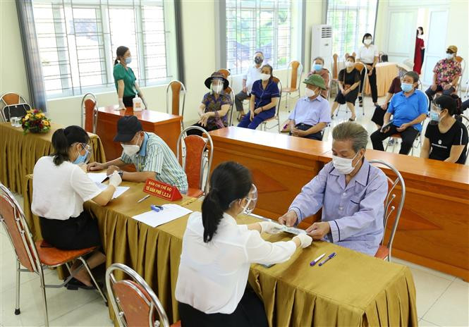 Des personnes défavorisées liées au Covid-19 au quartier de Nguyên Trai, arrondissement de Thanh Xuân, à Hanoi, reçoivent des assistances financières. Photo: VNA 