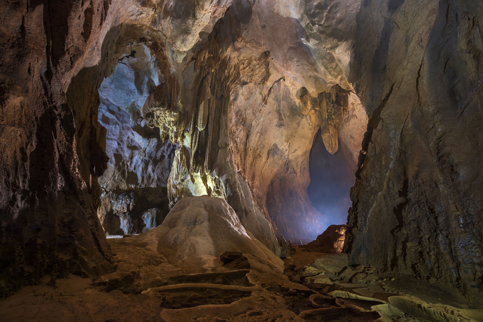 L'entrée de la grotte est assez grande et descend en pente. Les touristes sont équipés d'équipements pour assurer leur sécurité.
