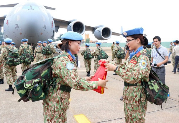 Des femmes soldats replient le drapeau national et sont prêtes à partir en mission. Photo: VNA 
