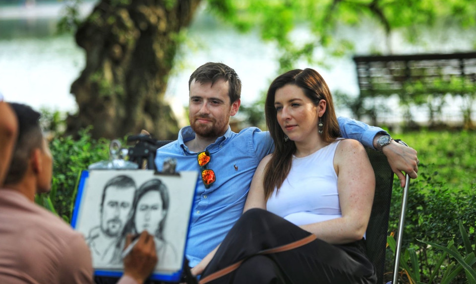 Des visiteurs se font croquer par des artistes de rue au bord du lac Hoan Kiem, à Hanoï.
