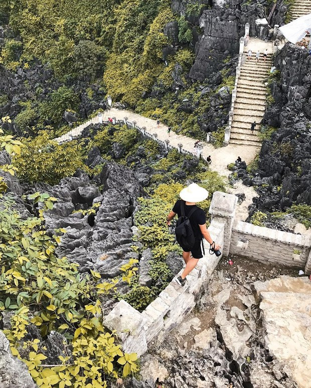 Photo: Vietnamplus Il y a une colline rocheuse parsemée de près de 500 marches menant au sommet couvert de tours, le faisant ressembler à une grande muraille miniature. Les deux côtés de la route sont décorés de statues en pierre sophistiquées de dragons et de phénix construites dans le style de la dynastie des Trân (1225-1400). Les touristes qui se rendent à cet endroit tentent souvent de conquérir le sommet de la montagne, ce qui les amènera à l’une des vues les plus emblématiques du Vietnam - une vue panoramique sur de pittoresques chaînes de montagnes calcaires et des rizières.