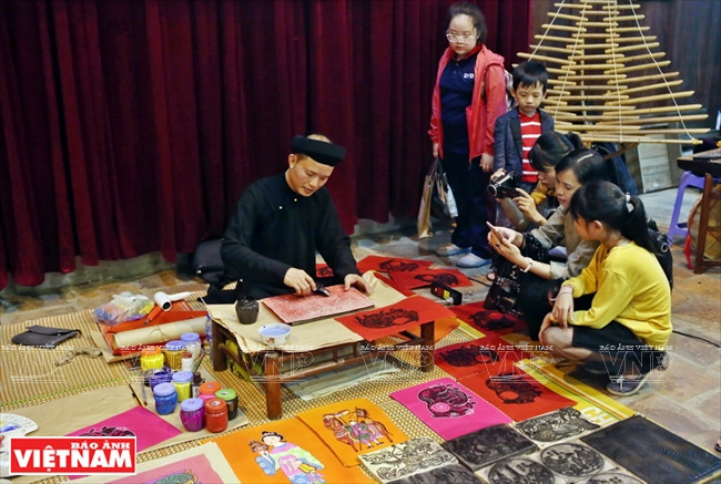 Des étudiants et visiteurs regardent des œuvres produits par un artisan du village de Kim Hoang.