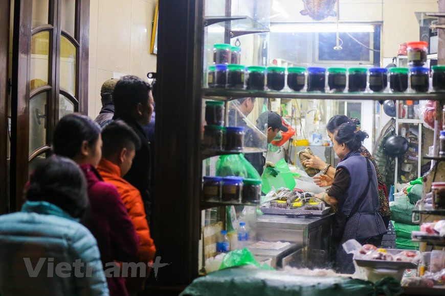 Selon le propriétaire de Quoc Huong, seulement environ 500 banh chung sont transférés au magasin dans le matin du 30e jour du 12e mois lunaire. En particulier, chaque banh chung est vendu au prix de 70.000 dôngs. Les prix des autres produits alimentaires du magasin comme thit bo kho (viande de boeuf séchée), nem chua (sorte de viande de porc fermentée enveloppée dans une feuille de bananier), gio cha (pâté de porc),... restent inchangés. Les saveurs traditionnelles des produits alimentaires du magasin Quoc Huong sont très appréciées par les Hanoïens, notamment des personnes âgées. C'est pourquoi le magasin est toujours bondé à chaque Nouvel An lunaire. Photo: Vietnam+