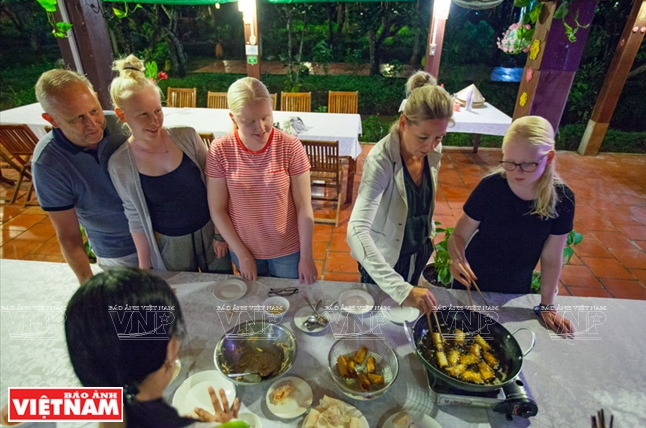 Des touristes étrangers sont initiés à la préparation des spécialités culinaires locales avant de les déguster à Bên Tre.