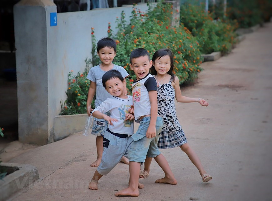 Des enfants d'un village de réinstallation de personnes issues de l'ethnie Thaï noir. En parcourant ces régions, vous serez surpris par la gentillesse de nombreux enfants qui sont assez pauvres matériellement mais riches en capacité de remplir les autres de joies et de sentiments agréables. Malgré le manque de biens matériels, les enfants des minorités ethniques locales restent innocents avec des yeux amicaux et un sourire radieux, exprimant une joie intérieure qui semble sans limite. Lorsqu'ils ne doivent pas aller à l'école, ils transforment les chemins en terrains de jeux. Les Thaï sont installés essentiellement dans le Nord et le Centre septentrional. Les Thaï noirs sont l’un des deux groupes principaux de cette ethnie : les noirs et les blancs, ainsi identifiés à cause de leur tenue vestimentaire. Leurs maisons diffèrent, aussi. Photo: VietnamPlus
