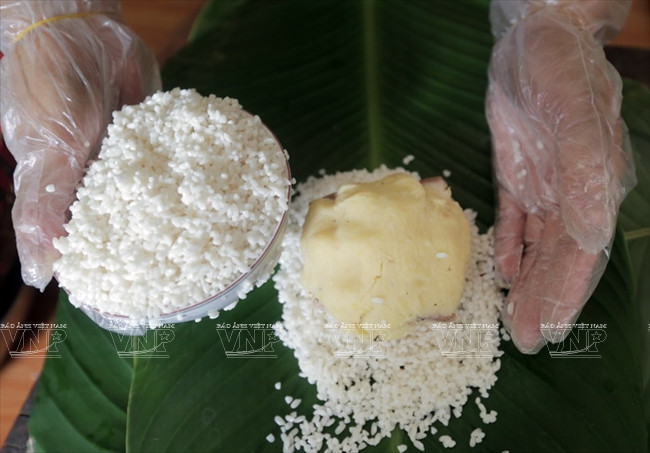 Une couche de riz gluant est étendue sur les feuilles de bananier, on ajoute au-dessus la garniture, puis on superpose une autre couche de riz gluant.