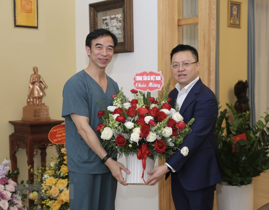 Le Quoc Minh, membre du Comité central du Parti, secrétaire du Comité du Parti de la VNA, directeur général adjoint de la VNA, offre des fleurs au directeur de l'hôpital de Bach Mai, Nguyen Quang Tuan. Photo: VNA