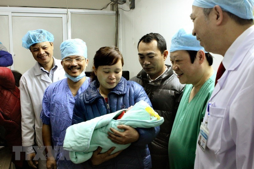  Nguyen Viet Tien, vice-ministre de la Santé (chemise bleue, à droite), et un bébé né grâce à la maternité de substitution en 2016. Photo: VNA