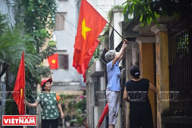 Les gens brandissent le drapeau national le 2 septembre dans la rue Doi Can à Hanoï.