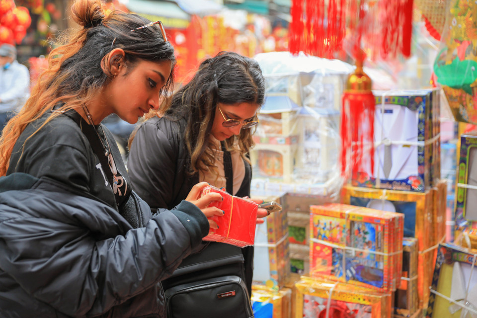 Des touristes étrangers achètent des enveloppes pour l'argent porte-bonheur dans la rue Hang Ma. Photo : VNA