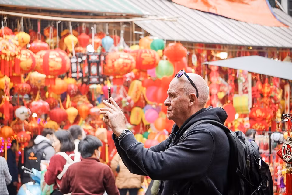  Les touristes étrangers apprécient l'atmosphère du marché aux fleurs de Hang Luoc. Photo : VNA 