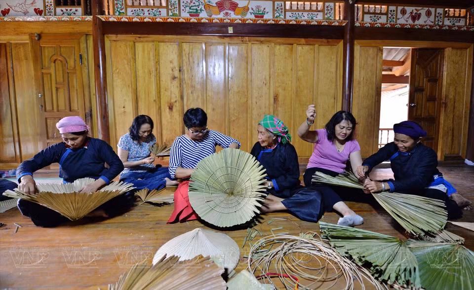  Certains visiteurs à Ban Lien ont la chance d'apprendre à fabriquer ces chapeaux coniques. Photo : VI 