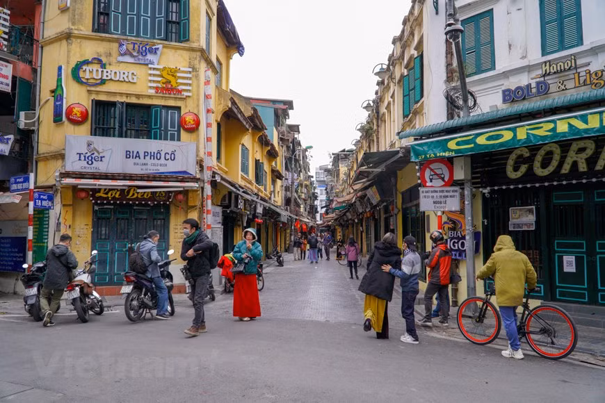 Des gens posent pour des photos dans la rue Ta Hiên, arrondissement de Hoàn Kiêm. Avant la propagation de l’épidémie de COVID-19, la rue Ta Hiên, surnommée la "rue des Tây” (Tây = Occidentaux), était réputée pour sa vie nocturne des plus animées. Ses stands de bière pression sur le trottoir proposaient toutes sortes de plats tels que cailles et calmars grillés, nem chua (hachis de porc fermenté et couenne), frites, phở xào bò (nouilles de riz à la viande de bœuf sautées)... Tout le monde se retrouvait coude-à-coude dans une joyeuse ambiance potache. Et puis, il y aussi des bars de nuit. Mais tout cela, c'était avant le coronavirus. Photo: VietnamPlus