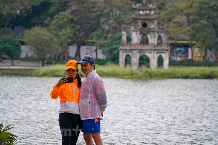 Un couple pose pour une photo au bord du lac de Hoan Kiêm à Hanoï. Le lac, l'une des destinations les plus attrayantes de la ville, est si calme et paisible durant les vacances du Têt traditionnel. Le lac Hoan Kiêm (Épée restituée), vestige de l’ancienne rivière Nhi Ha, est un site pittoresque de la capitale vietnamienne, entouré des rues Hàng Khay, Lê Thai To et Dinh Tiên Hoàng. À la fin du XIXe siècle, le lac fut choisi par les Français comme centre du processus de planification de la ville. À partir de là, Hanoï s'est progressivement étendue. Le lac et ses alentours constituent l’une des principales attractions de la capitale vietnamienne. Les environs du lac présentent une verdure luxuriante et des édifices de deux ou trois étages datant de colonisation française. Photo: VietnamPlus