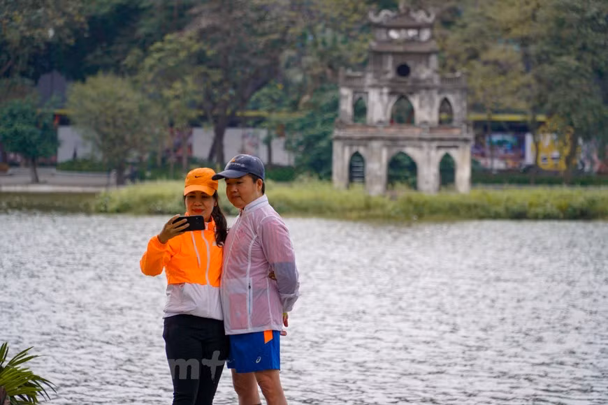 Un couple pose pour une photo au bord du lac de Hoan Kiêm à Hanoï. Le lac, l'une des destinations les plus attrayantes de la ville, est si calme et paisible durant les vacances du Têt traditionnel. Le lac Hoan Kiêm (Épée restituée), vestige de l’ancienne rivière Nhi Ha, est un site pittoresque de la capitale vietnamienne, entouré des rues Hàng Khay, Lê Thai To et Dinh Tiên Hoàng. À la fin du XIXe siècle, le lac fut choisi par les Français comme centre du processus de planification de la ville. À partir de là, Hanoï s'est progressivement étendue. Le lac et ses alentours constituent l’une des principales attractions de la capitale vietnamienne. Les environs du lac présentent une verdure luxuriante et des édifices de deux ou trois étages datant de colonisation française. Photo: VietnamPlus