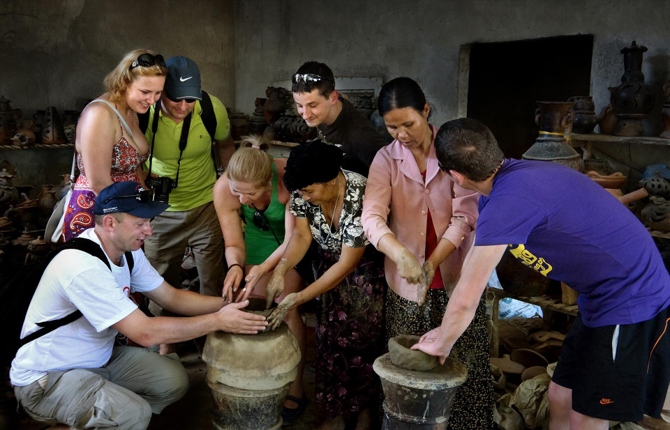 Touristes visitant l'usine de poterie de Bau Truc pour découvrir des secrets de la fabrication des poteries Cham. Photo : VI