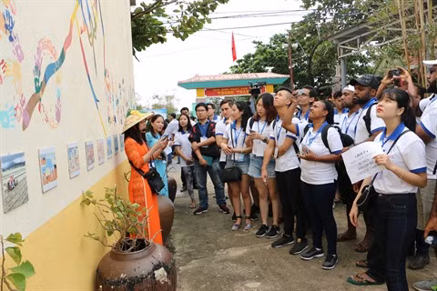 Les jeunes membres du Forum des Voix du futur s’informent sur les dessins muraux dans le village Bich Hoa.