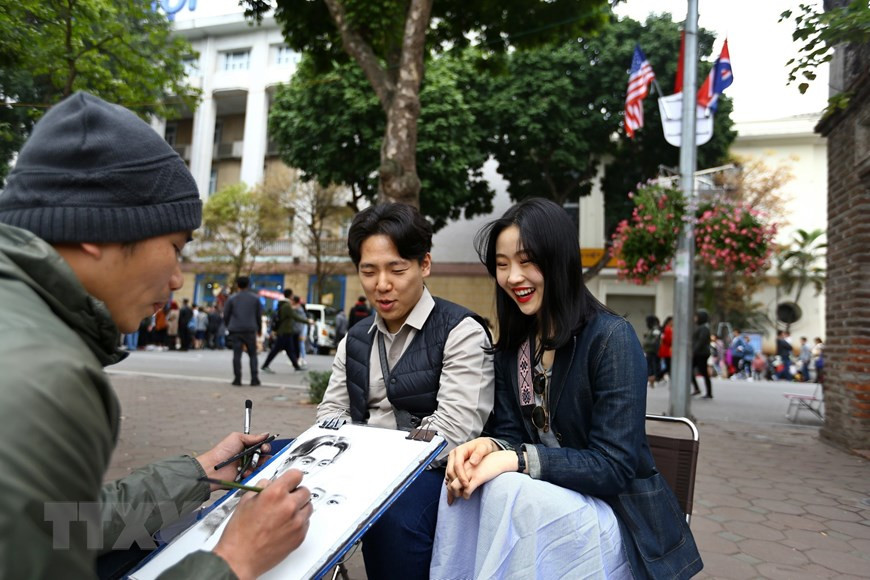 Les portraits des touristes étrangers sont réalisés par un artiste vietnamien autour du lac Hoan Kiem.
