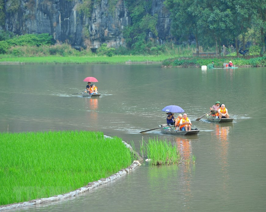  Les touristes étrangers font une belle balade en bateau à Tam Coc.