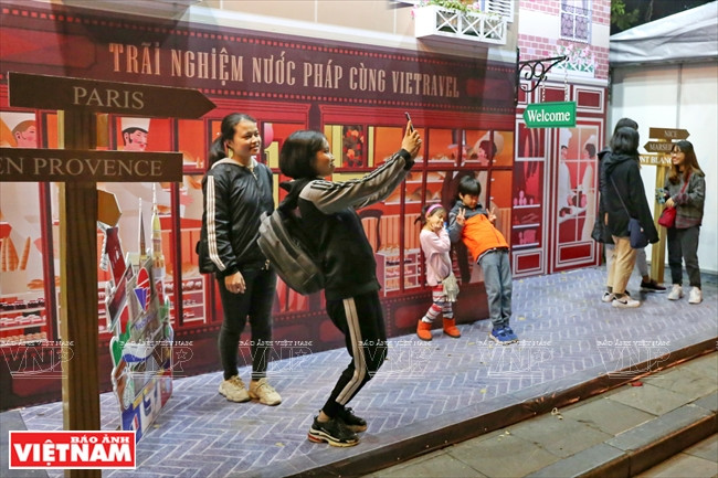  Des visiteurs posent dans la zone imitant des boutiques de la France.