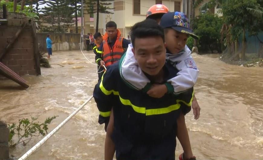  Les forces compétentes du district de Moc Chau aident un enfant à traverser une route inondée. 