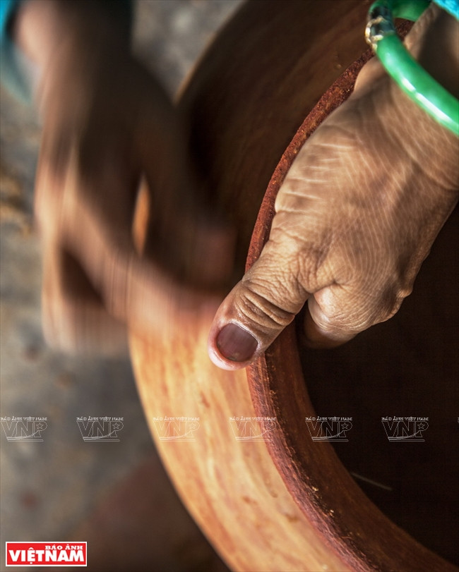  Un potier Cham polit la face extérieure d’une poterie avec un gravier 