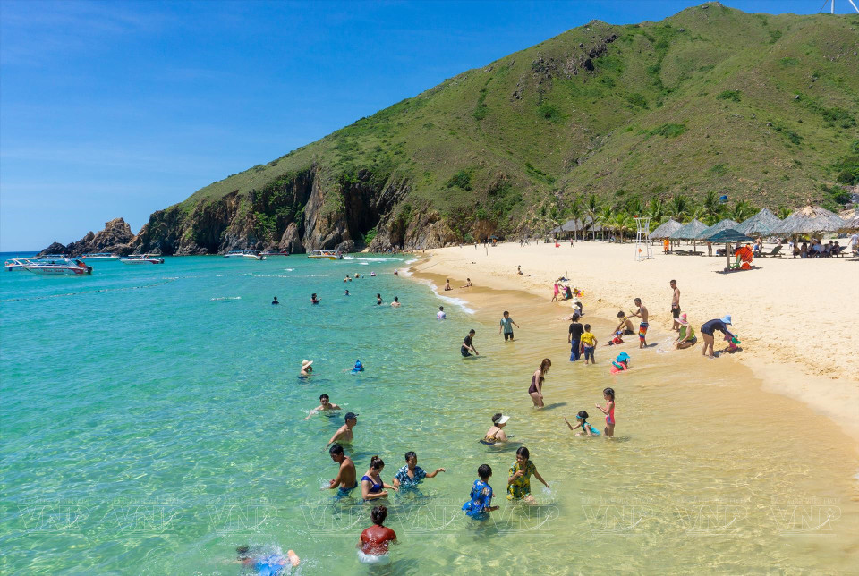 Des touristes se détendent dans la mer bleue et fraîche de la plage de la péninsule de Ky Co.