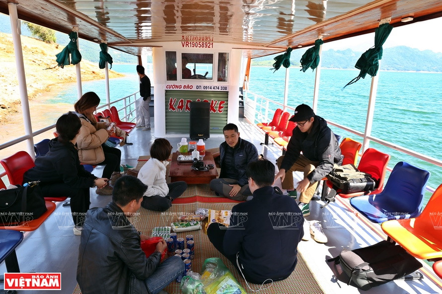 Des touristes prennent le bateau pour aller au village de Da Bia.